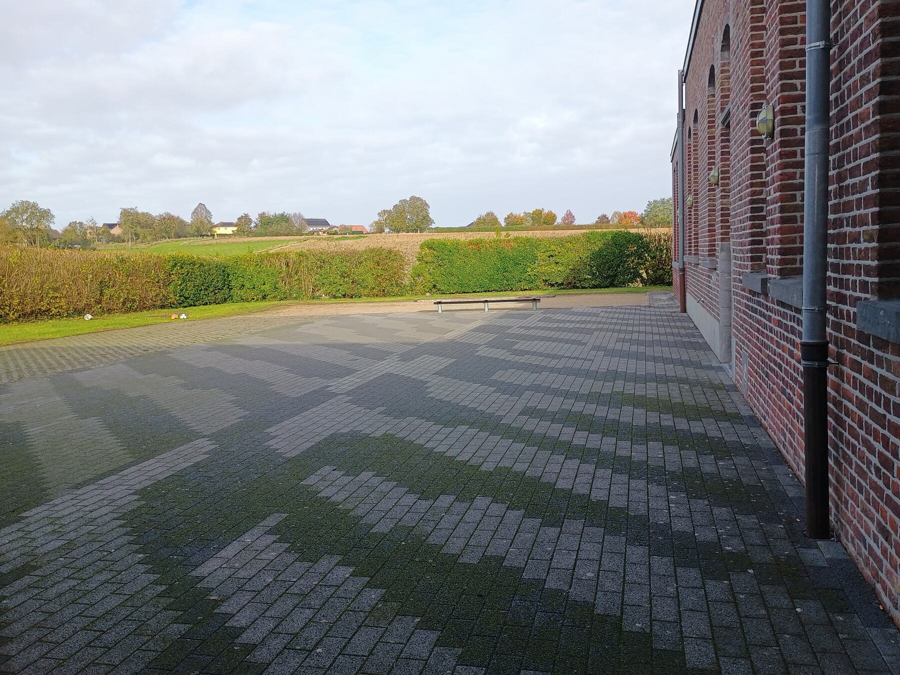 Verhard terras achter het gebouw met zicht op de velden